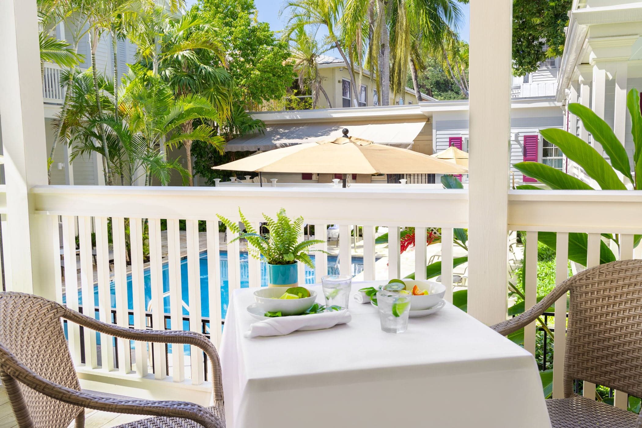 The porch off of room 32 at Marquesa with a patio table and2 chairs overlooking the pool