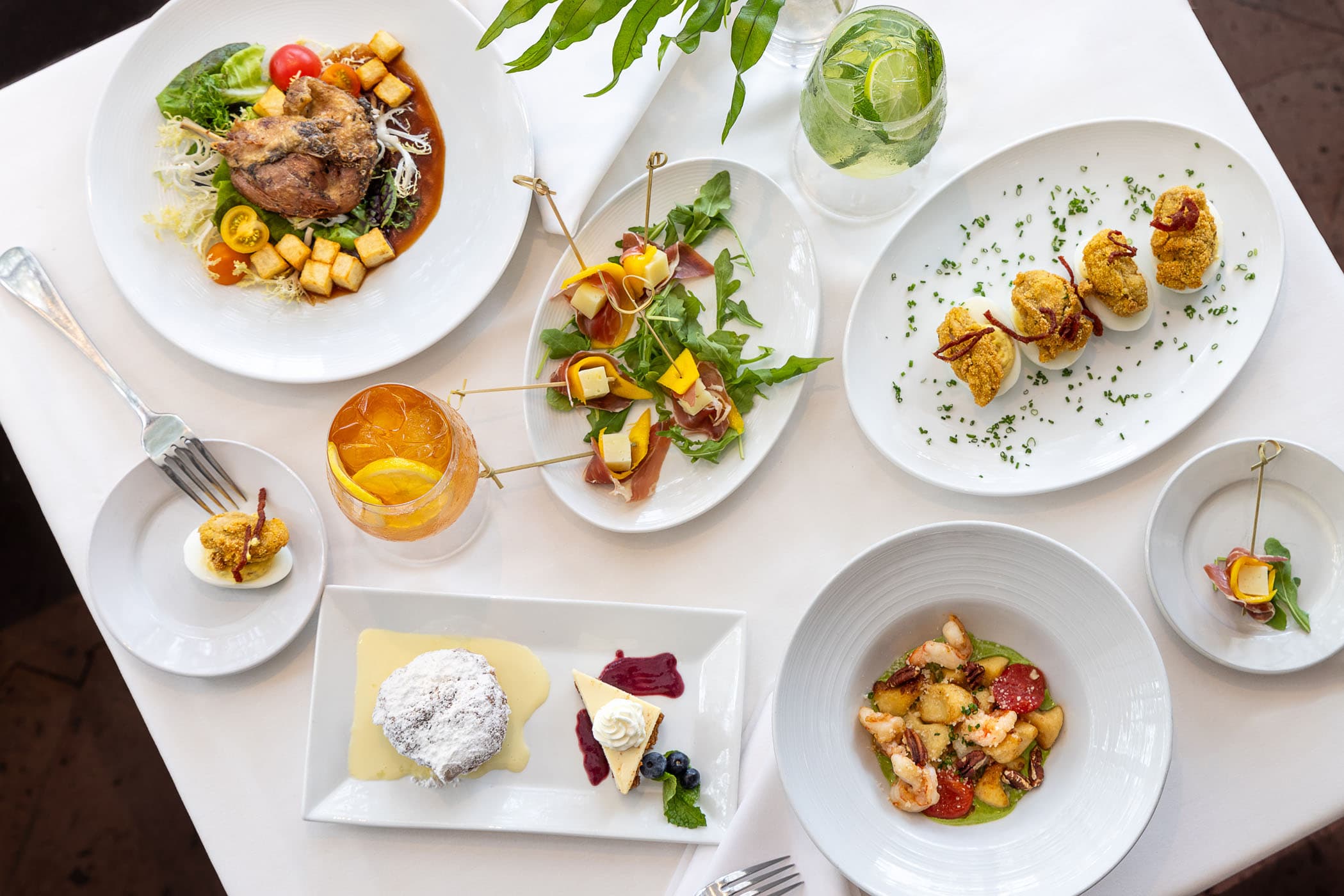 A spread of various menu items and 2 cocktails at Marquesa