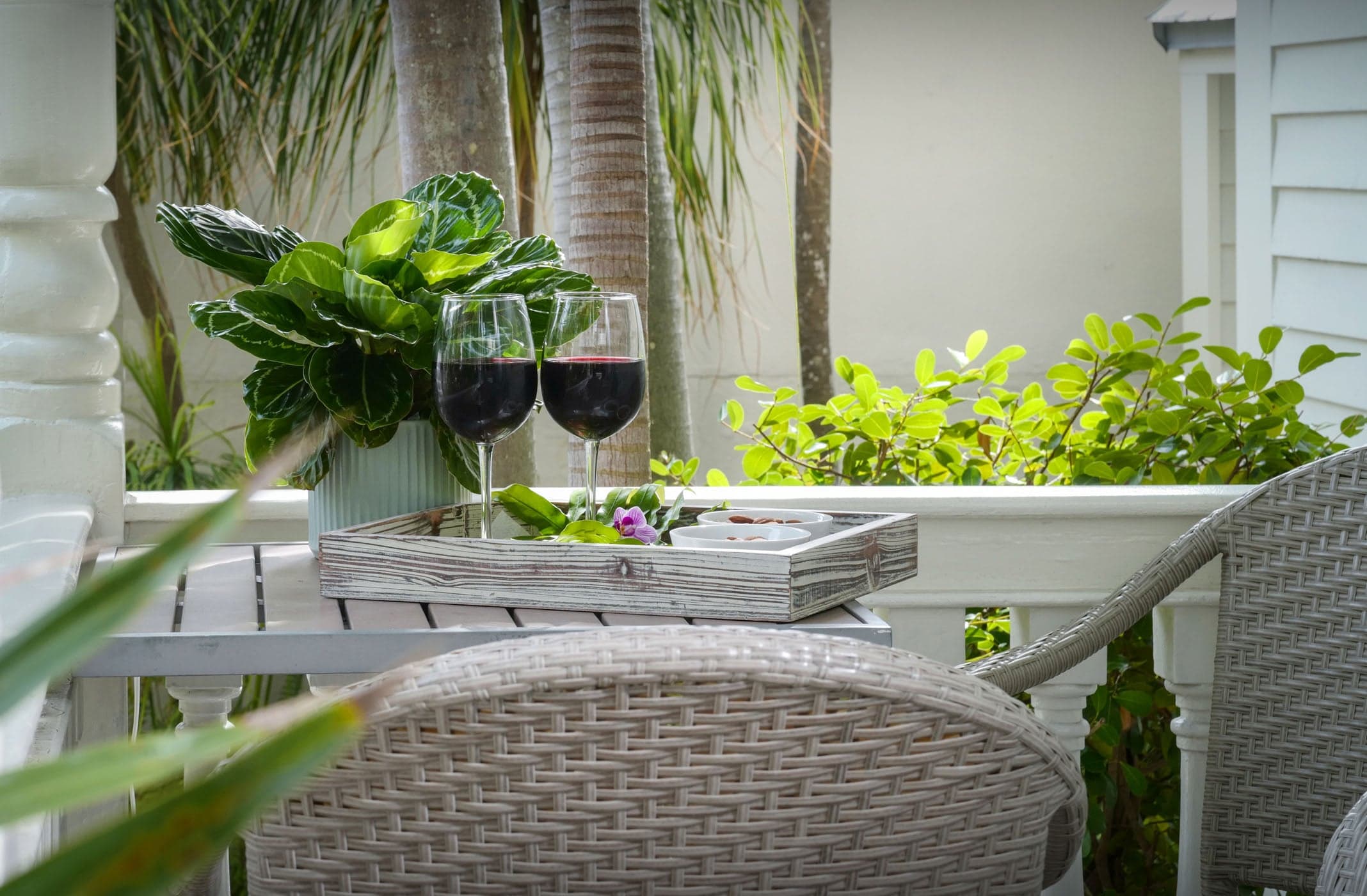 2 glasses of red wine and snacks on a patio table