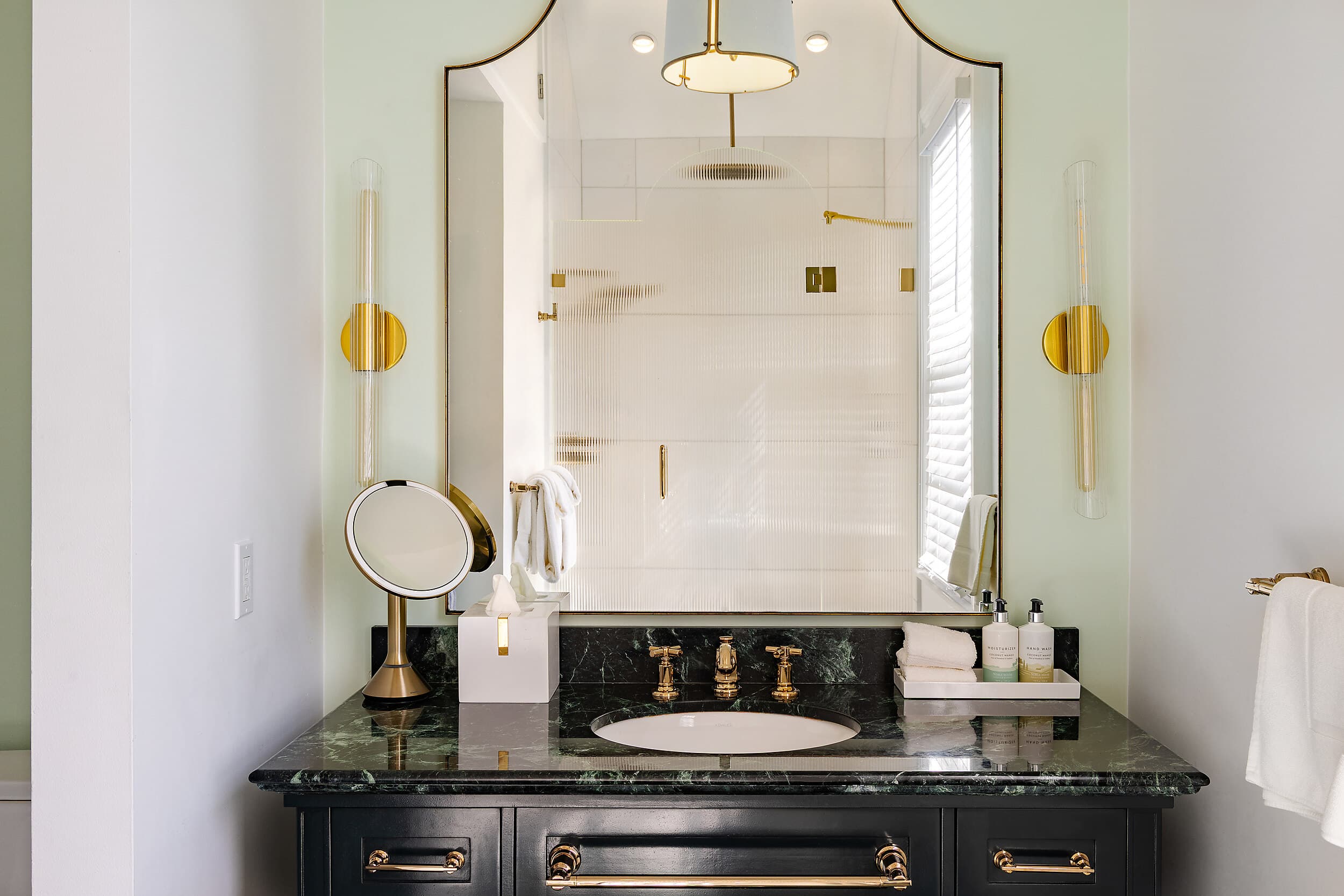 Green marble vanity with gold fixtures in a Marquesa Hotel Key West bathroom