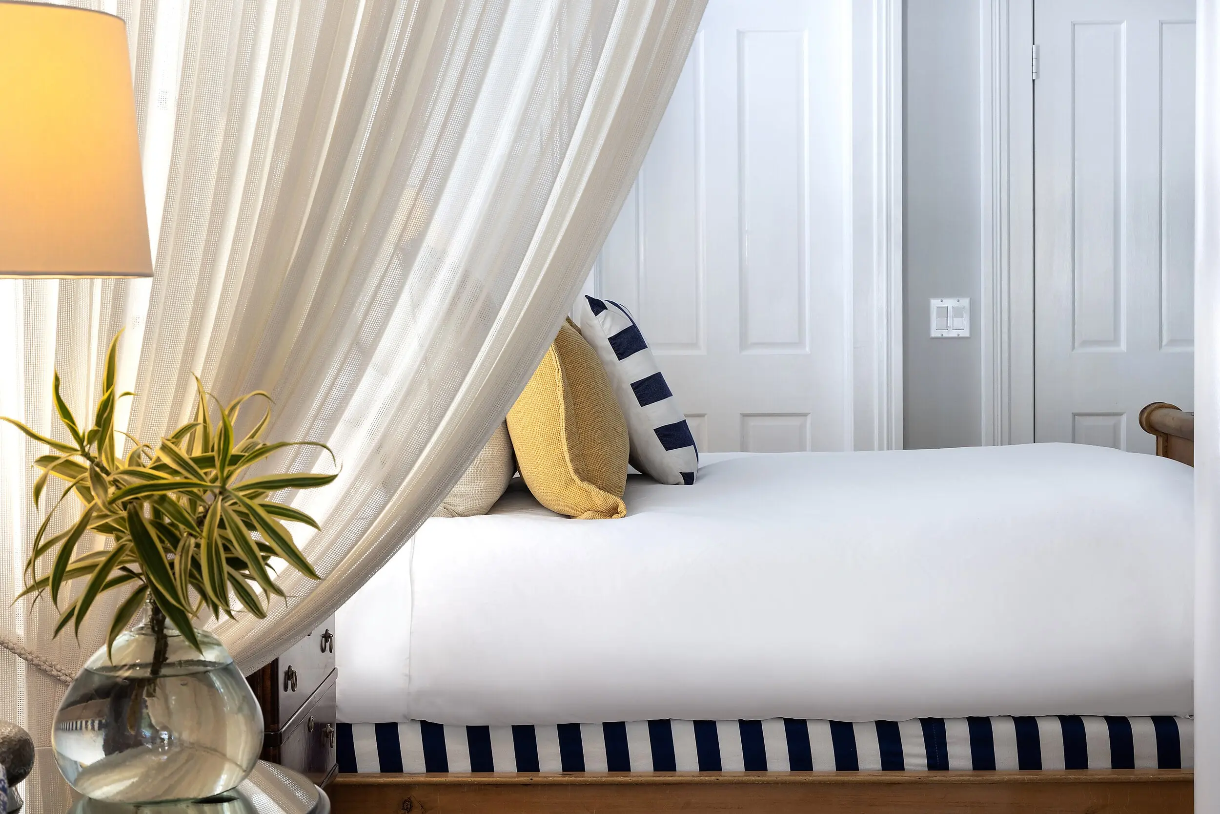 Canopy bed with sheer drapery and accent pillows at the Marquesa Hotel Key West