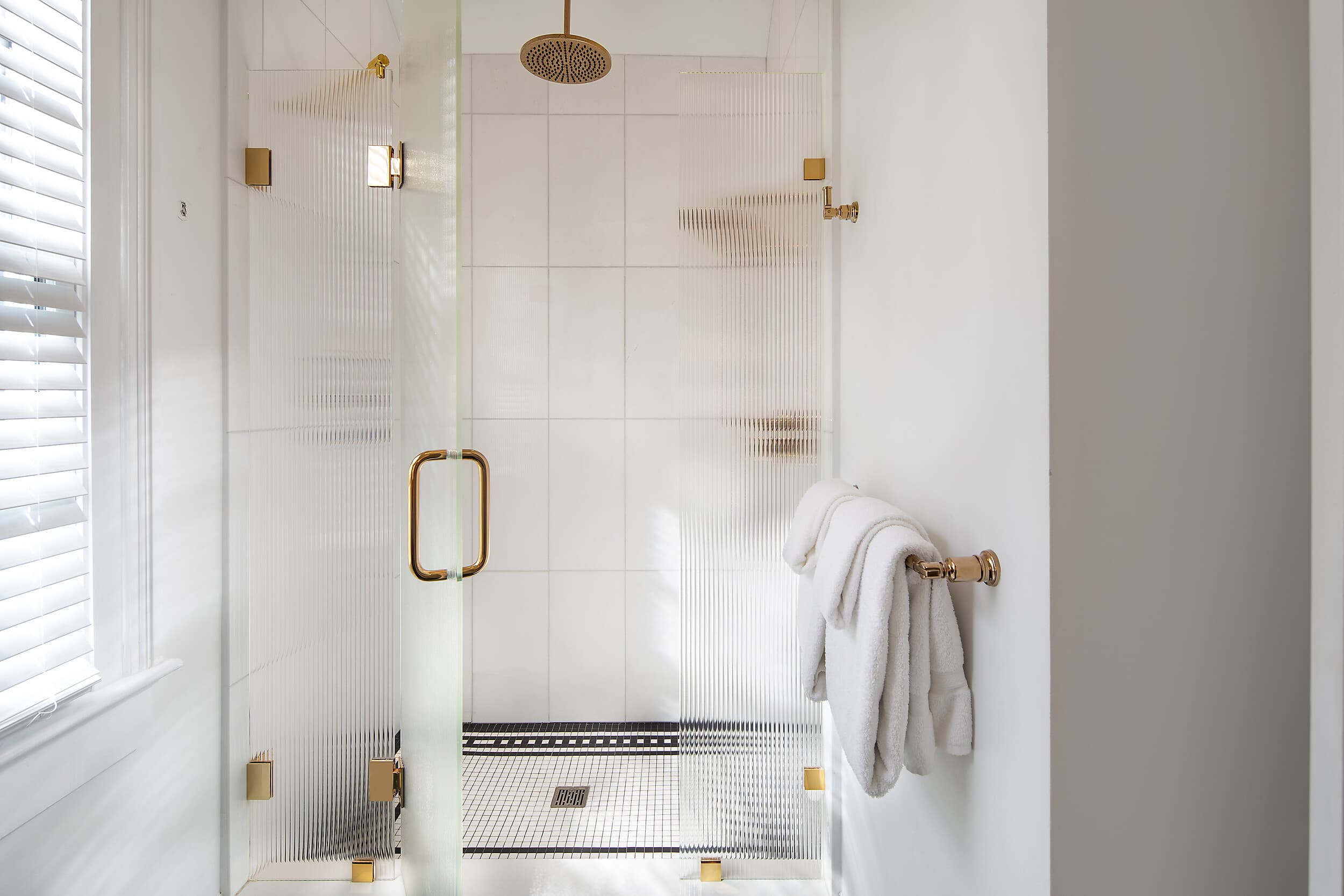 Glass walk-in rainfall shower with gold fixtures at the Marquesa Hotel Key West
